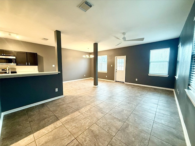 unfurnished living room featuring light tile patterned flooring, ceiling fan with notable chandelier, and sink