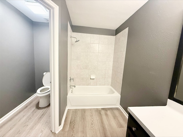 full bathroom with toilet, tiled shower / bath, vanity, and hardwood / wood-style floors