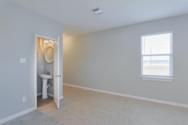 unfurnished room with light tile patterned floors and sink