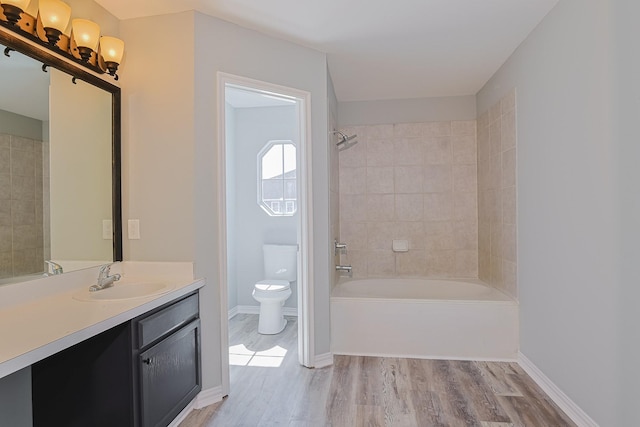 full bathroom featuring toilet, tiled shower / bath, wood-type flooring, and vanity