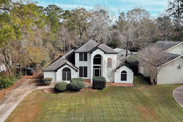 view of front of house featuring a front yard, concrete driveway, roof with shingles, and brick siding