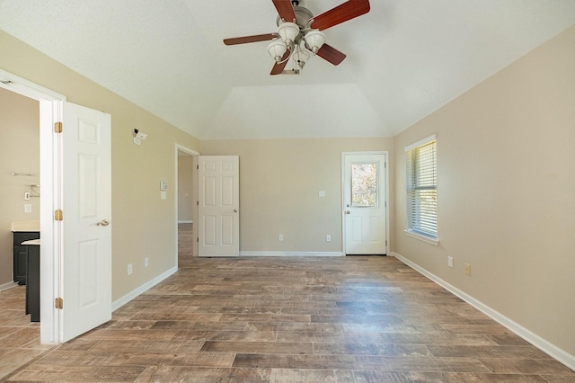 empty room with lofted ceiling, ceiling fan, wood finished floors, and baseboards