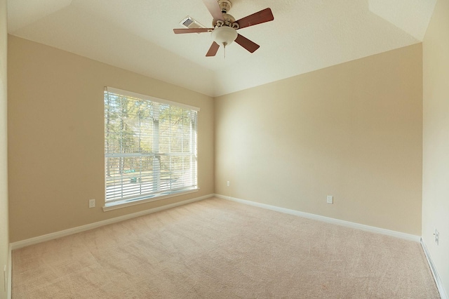 empty room with light colored carpet, visible vents, vaulted ceiling, ceiling fan, and baseboards