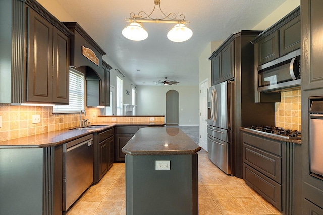 kitchen with ceiling fan, appliances with stainless steel finishes, a center island, hanging light fixtures, and sink