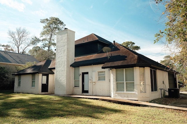 rear view of property featuring a yard, brick siding, a chimney, and a shingled roof