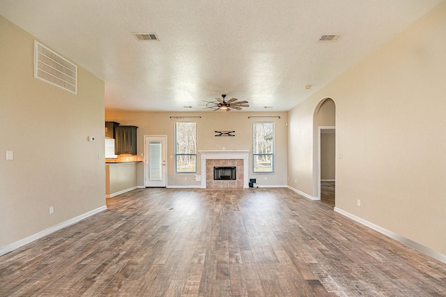 unfurnished living room with dark wood-style floors, visible vents, and ceiling fan