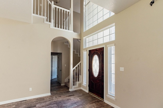 entrance foyer with dark wood-style floors, a wealth of natural light, baseboards, and stairs