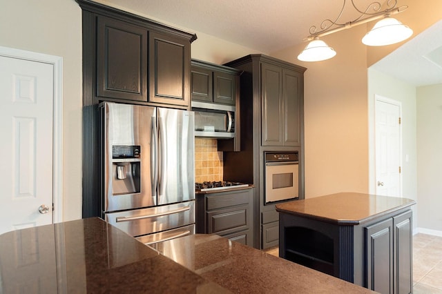 kitchen featuring decorative backsplash, dark countertops, a kitchen island, appliances with stainless steel finishes, and pendant lighting