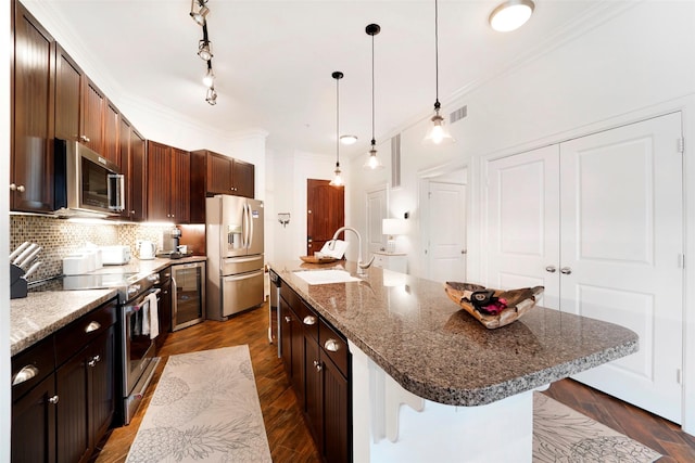 kitchen with a breakfast bar, a kitchen island with sink, sink, and stainless steel appliances