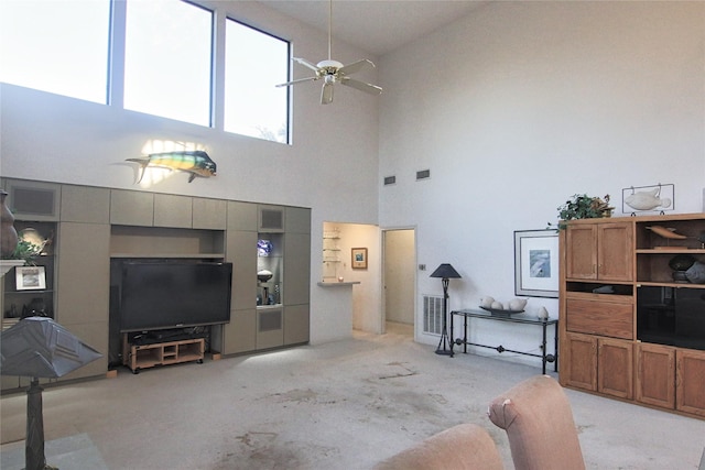 living room with ceiling fan, light carpet, and a towering ceiling