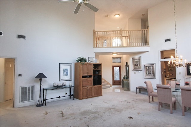 living room with ceiling fan with notable chandelier, a high ceiling, and carpet flooring