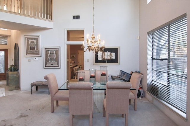 carpeted dining area with an inviting chandelier and a high ceiling