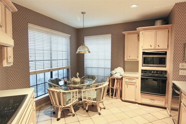 kitchen with light brown cabinetry, pendant lighting, black appliances, and light tile patterned flooring