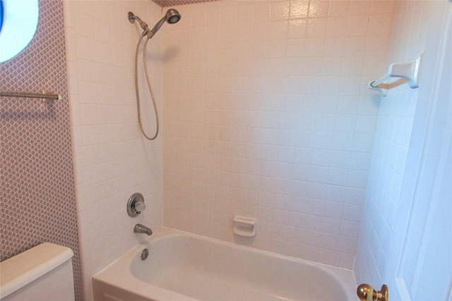 bathroom with toilet and tiled shower / bath