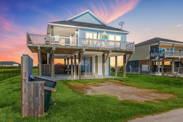 back house at dusk with a patio, a garage, a deck, and a lawn