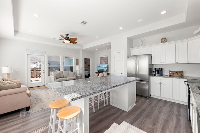 kitchen with stainless steel fridge, a kitchen breakfast bar, and a raised ceiling