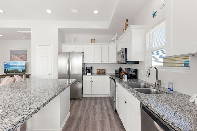 kitchen with light stone counters, stainless steel appliances, sink, and white cabinets