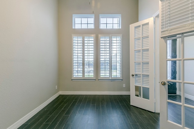 unfurnished room featuring a high ceiling and dark hardwood / wood-style floors