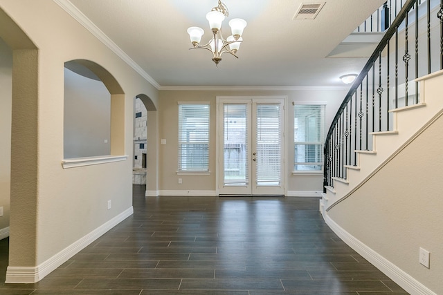 foyer with crown molding, french doors, and an inviting chandelier