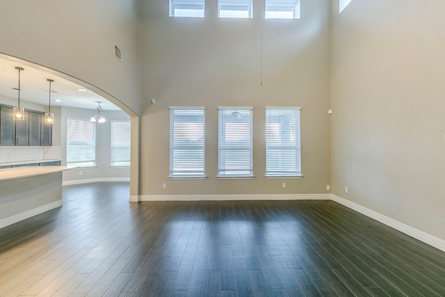 interior space featuring a towering ceiling, a chandelier, and dark hardwood / wood-style floors