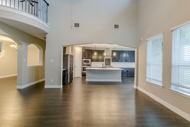 unfurnished living room with sink, a towering ceiling, and dark hardwood / wood-style flooring