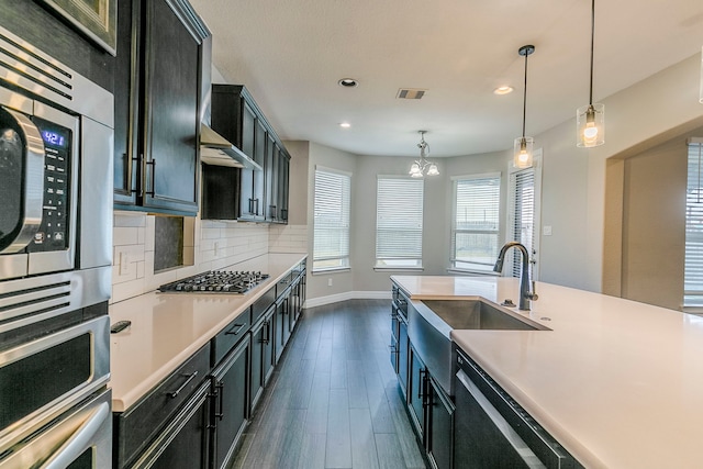 kitchen featuring pendant lighting, sink, stainless steel appliances, dark hardwood / wood-style flooring, and a chandelier