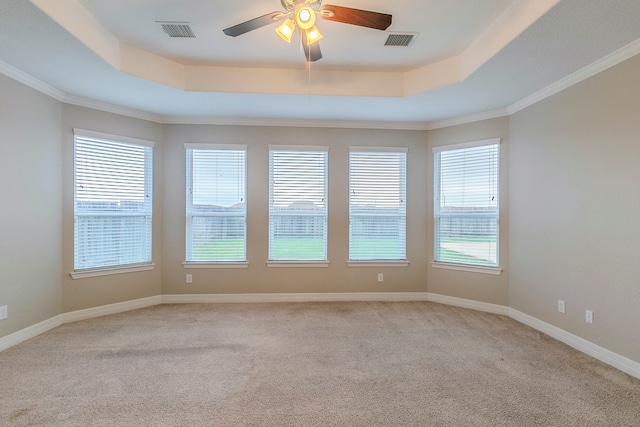 unfurnished room featuring ceiling fan, crown molding, light colored carpet, and a tray ceiling