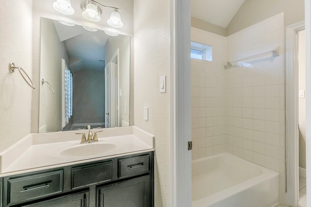 bathroom featuring vaulted ceiling, bathing tub / shower combination, and vanity