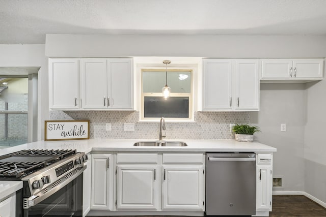 kitchen with white cabinets, decorative light fixtures, stainless steel appliances, tasteful backsplash, and sink