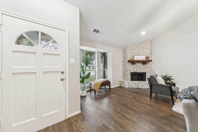 foyer featuring lofted ceiling, a fireplace, dark hardwood / wood-style flooring, and a textured ceiling