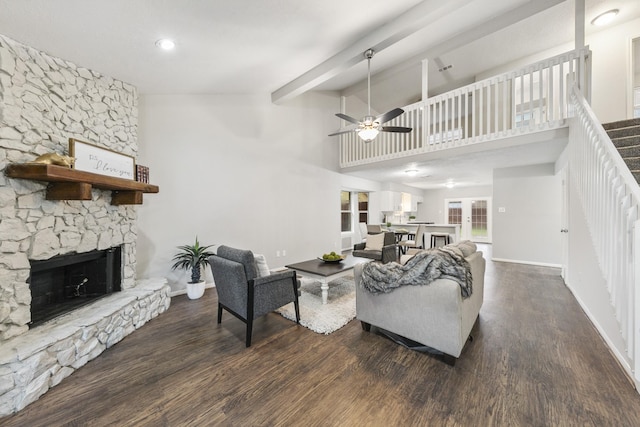 living room with ceiling fan, dark hardwood / wood-style floors, a fireplace, and a towering ceiling