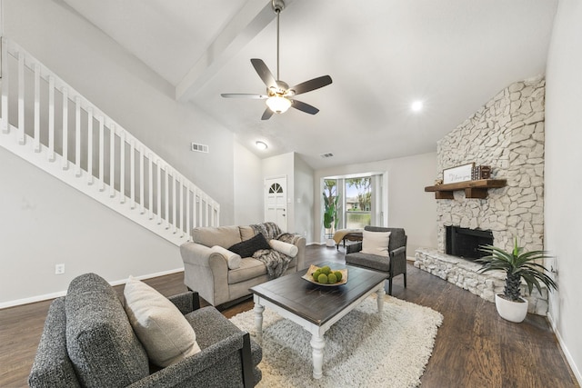 living room featuring dark hardwood / wood-style floors, vaulted ceiling with beams, a stone fireplace, and ceiling fan