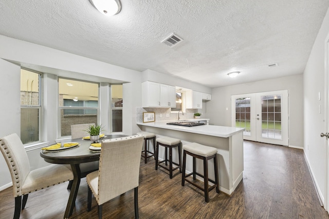 kitchen featuring dark wood-type flooring, white cabinetry, french doors, decorative backsplash, and kitchen peninsula