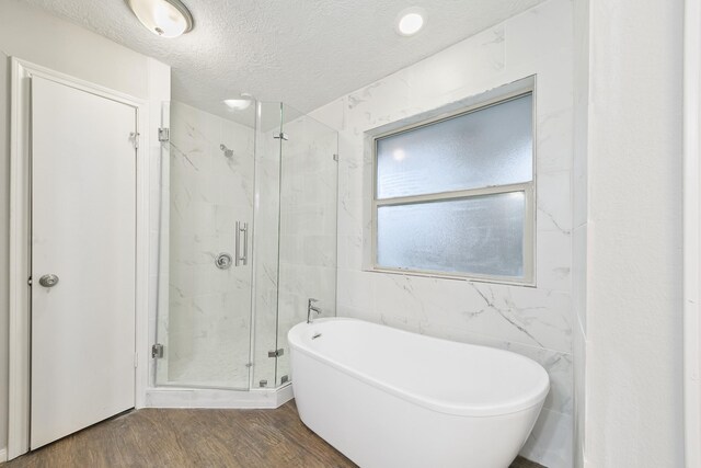 bathroom with tile walls, plus walk in shower, a textured ceiling, and hardwood / wood-style floors