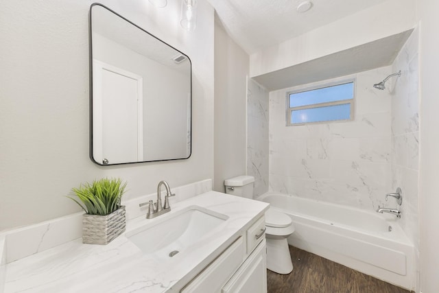 full bathroom featuring hardwood / wood-style floors, a textured ceiling, tiled shower / bath, vanity, and toilet