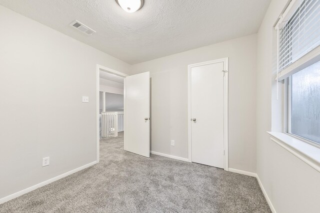 unfurnished bedroom with light colored carpet and a textured ceiling