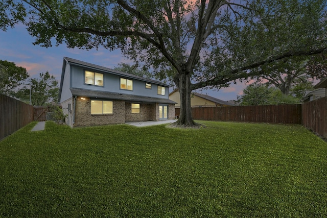 back house at dusk with a patio area and a yard