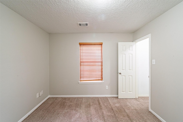 carpeted empty room with a textured ceiling