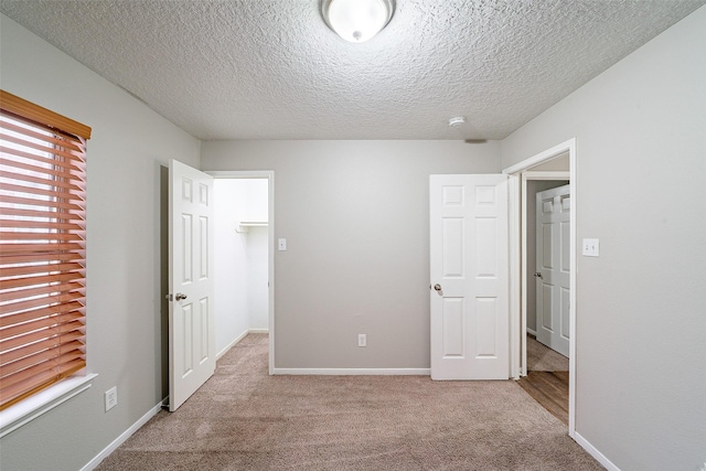 unfurnished bedroom with a textured ceiling and light carpet