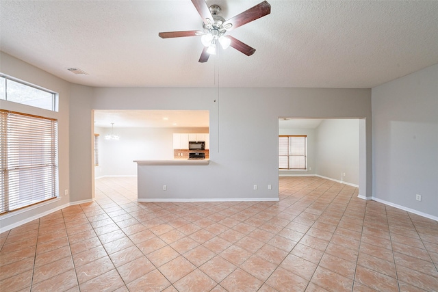 unfurnished living room with a textured ceiling, ceiling fan, and light tile patterned floors