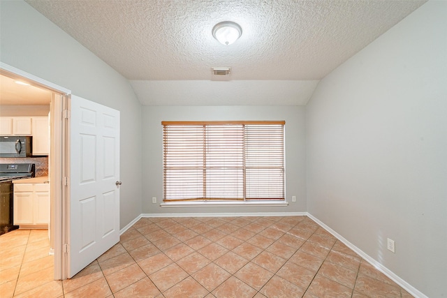 unfurnished room featuring a textured ceiling, lofted ceiling, and light tile patterned flooring