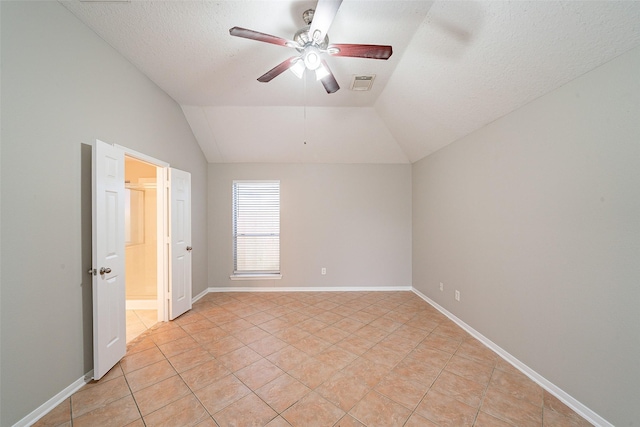 tiled spare room featuring ceiling fan, vaulted ceiling, and a textured ceiling