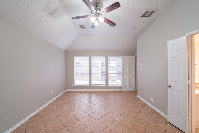 spare room with vaulted ceiling, ceiling fan, light tile patterned floors, and a textured ceiling