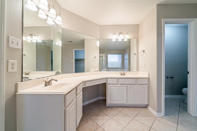 bathroom featuring toilet, a textured ceiling, tile patterned floors, and vanity