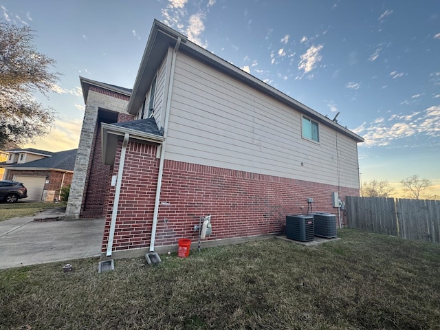 property exterior at dusk featuring central AC unit and a yard