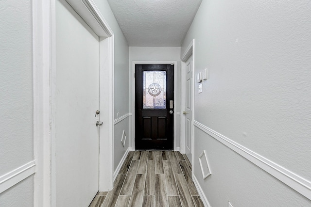 doorway featuring a textured ceiling and light hardwood / wood-style flooring