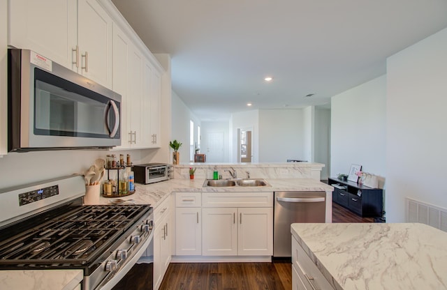 kitchen with white cabinetry, kitchen peninsula, appliances with stainless steel finishes, light stone countertops, and sink