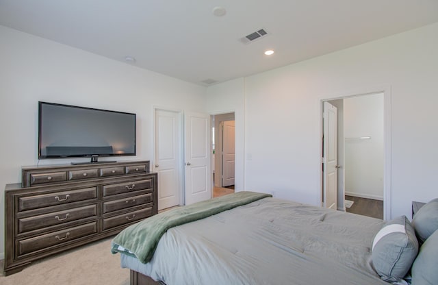 bedroom with light colored carpet, connected bathroom, and a closet