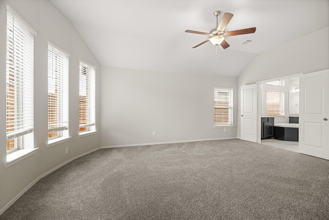 interior space featuring ensuite bathroom, visible vents, baseboards, vaulted ceiling, and carpet