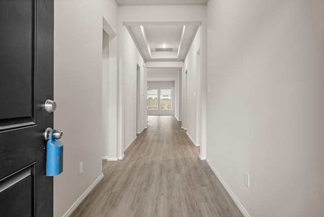 corridor with light wood finished floors, baseboards, and visible vents